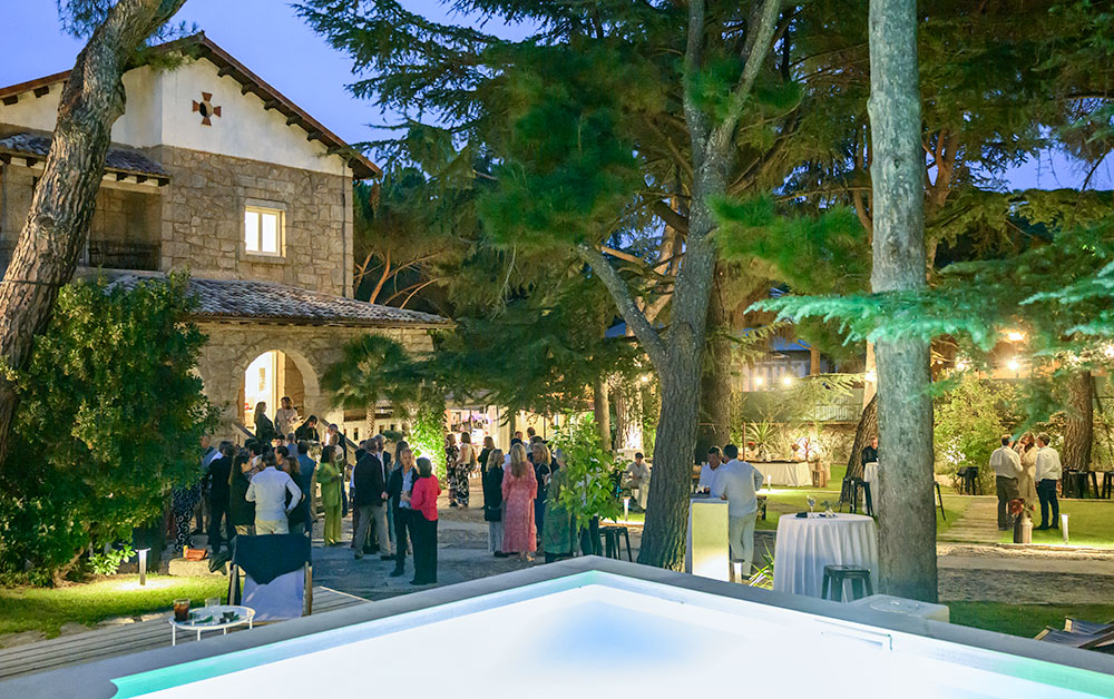 Finca para eventos Espacio1902 de noche con gran masía de piedra rústica iluminada y gente en la terraza.